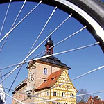 Ein Bild des Alten Rathauses von der Seite durch Fahrradspeichen hindurch.