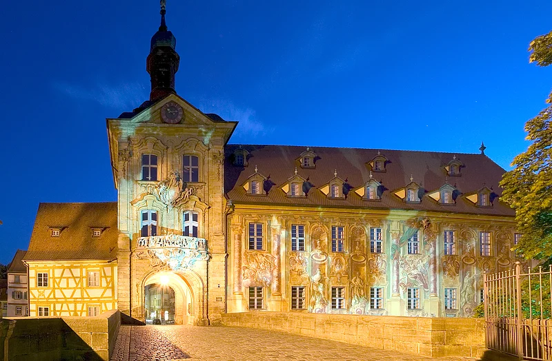 The Old Town Hall A bridge crossed the river already in the early 11 th century. Built in the middle of the 14th century, the town hall was rebuilt after a disasterous fire in 1440 by Bamberg's citizens. Michael Küchel redesigned it in rococo and baroque style between 1744-1756. Beside the beautiful architecture, in particular the fescos captivate by their plasticity.