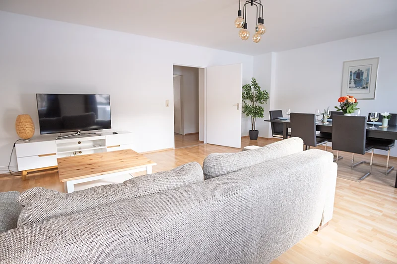 Wohnzimmer Ferienwohnung Bamberg fuer 6 Personen Helles Wohnzimmer der Ferienwohnung in Bamberg für bis zu 6 Personen mit großem Essbereich und direktem Zugang zum Balkon. Ideal für Familien und Gruppen nahe der Bamberger Altstadt.