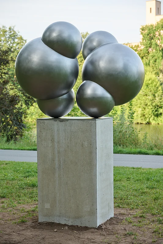 Skulptur Wassermoleküle The stainless steel figure by the Nuremberg artist Michaela Briet has been standing on the banks of the Adenauer in Bamberg since 2024 and is part of the “Art Encounters on the Canal” project of the Regnitz Cycle Path canal route.