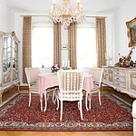 Elegantes Esszimmer mit großem Tisch, stilvollen Möbeln und Kronleuchter – ideal für entspannte Abende